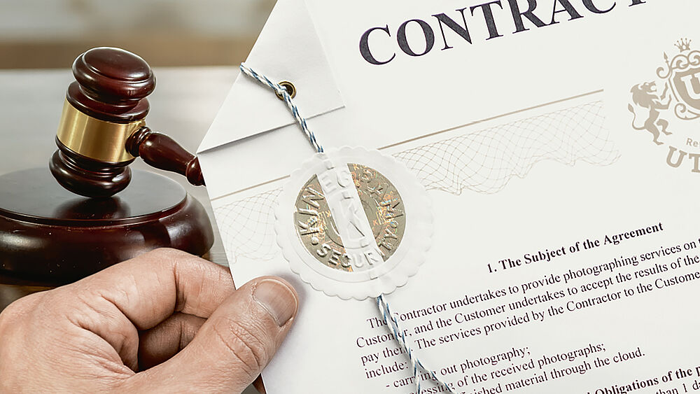 The KINEGRAM Notary Seal protects notary documents from fraud and manipulation. Image of hand holding a notary certificate stamped with a gold color secure KINEGRAM Notary Seal